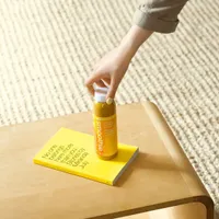 A hand placing a yellow bottle on a yellow book
