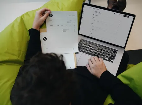 A strategist on a green beanbag working through printed briefs and a laptop