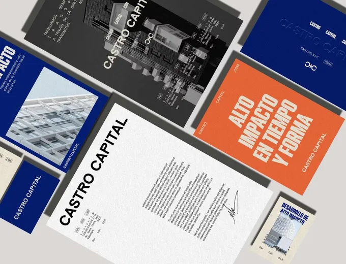 Castro Capital stationery and posters in blue, orange and black laid out on a grey table