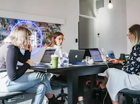 A creative team at work around a large table with laptops