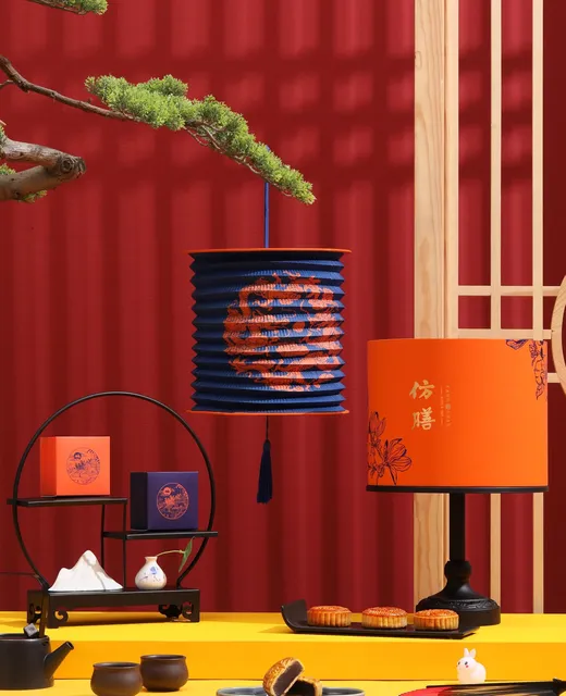 A red set with a blue paper lantern, an orange lamp and mooncakes on a yellow table
