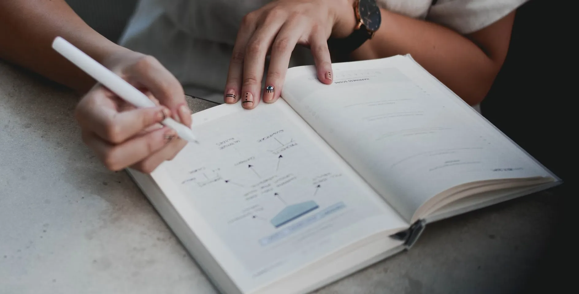 Hands sketching a user flow in an open notebook with a white pencil