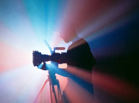 A camera operator filming on a set lit in blue and red